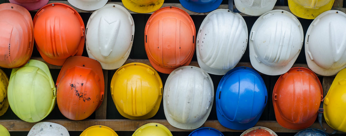 Multicoloured hardhats hung on a wall